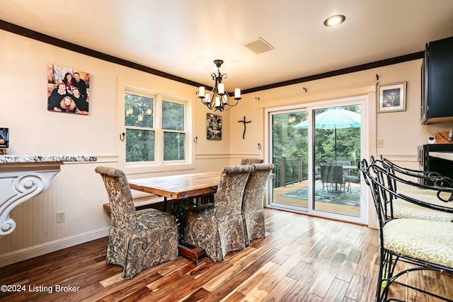 dining space featuring an inviting chandelier, hardwood / wood-style floors, and crown molding