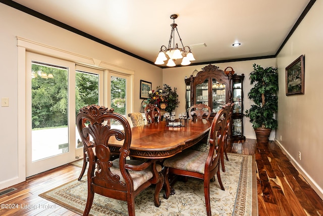 dining space featuring dark hardwood / wood-style flooring, crown molding, plenty of natural light, and an inviting chandelier