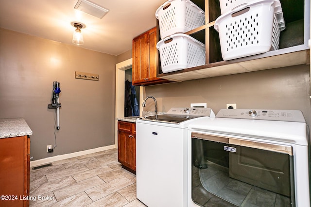 washroom with cabinets, sink, and washing machine and dryer