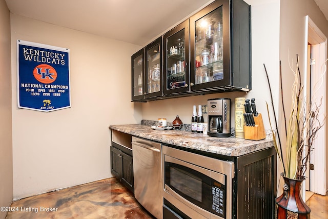 bar featuring stainless steel microwave and light stone counters