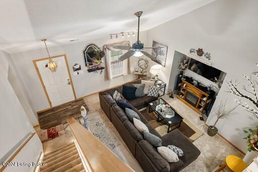 living room with ceiling fan, lofted ceiling, and a fireplace