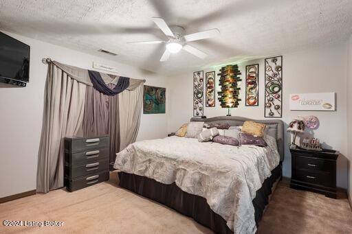 bedroom featuring ceiling fan, light colored carpet, and a textured ceiling