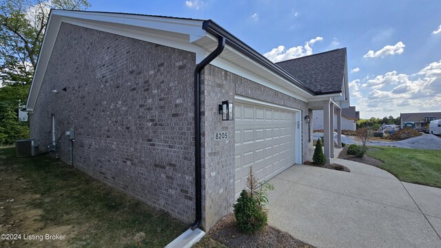 view of side of home with central AC unit and a garage