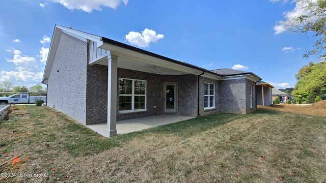 back of property with a yard and a patio