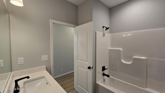 bathroom with washtub / shower combination, hardwood / wood-style flooring, and vanity