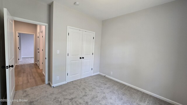 unfurnished bedroom with light colored carpet and a closet