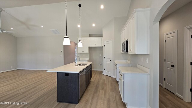 kitchen with pendant lighting, white cabinets, stainless steel appliances, sink, and a kitchen island with sink