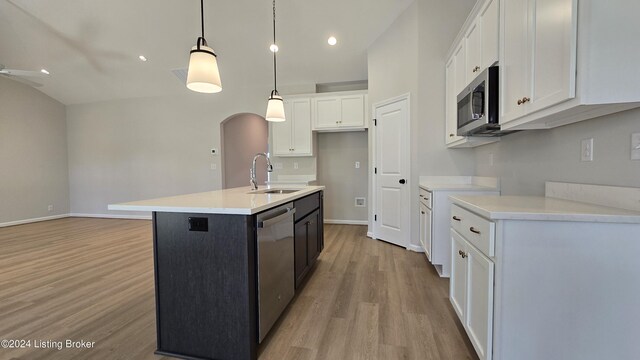 kitchen with white cabinets, appliances with stainless steel finishes, decorative light fixtures, an island with sink, and sink