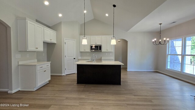 kitchen with sink, pendant lighting, white cabinetry, and a center island with sink