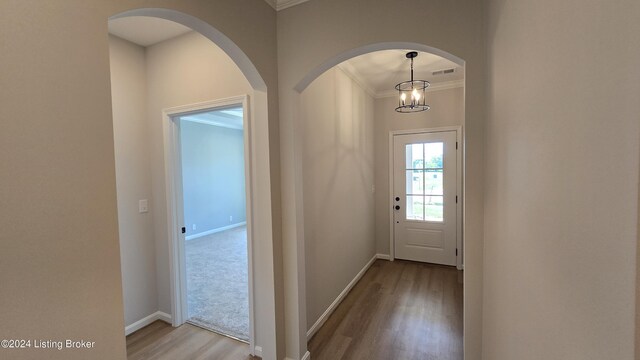 doorway with a chandelier, ornamental molding, and light hardwood / wood-style floors