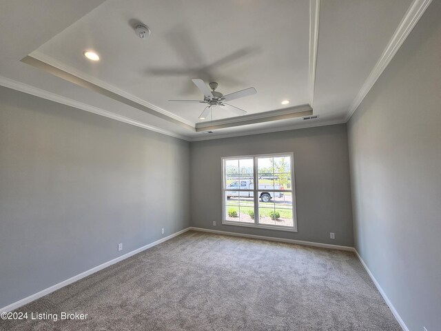 carpeted empty room featuring ceiling fan, ornamental molding, and a tray ceiling