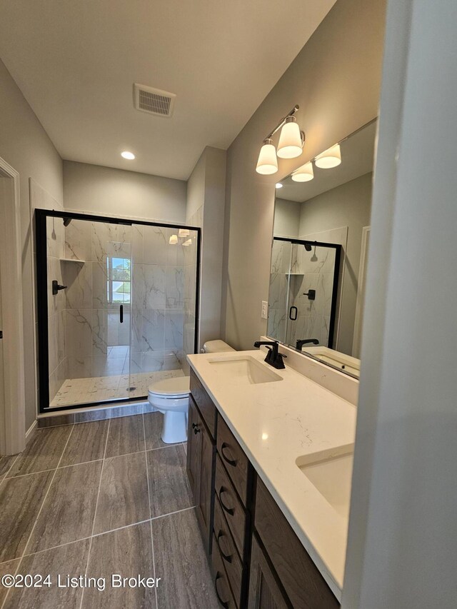 bathroom featuring a shower with shower door, toilet, and vanity