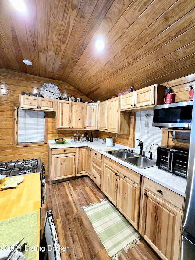 kitchen with lofted ceiling, appliances with stainless steel finishes, light brown cabinets, a sink, and wooden ceiling