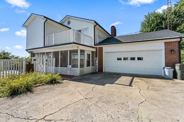 front facade with a garage, a sunroom, and a balcony