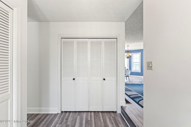 bedroom with a textured ceiling, a closet, a chandelier, and wood-type flooring