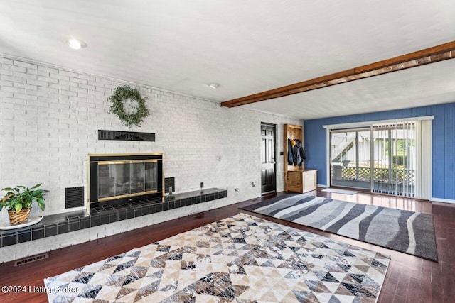 living room with beam ceiling, a brick fireplace, brick wall, and hardwood / wood-style flooring