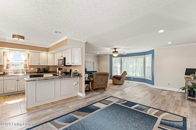 kitchen with a textured ceiling, white cabinets, ornamental molding, and appliances with stainless steel finishes