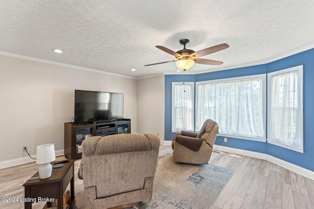 living room featuring ceiling fan, a textured ceiling, light hardwood / wood-style flooring, and ornamental molding