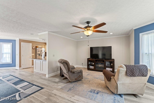 living room with ceiling fan, light wood-type flooring, crown molding, and a textured ceiling