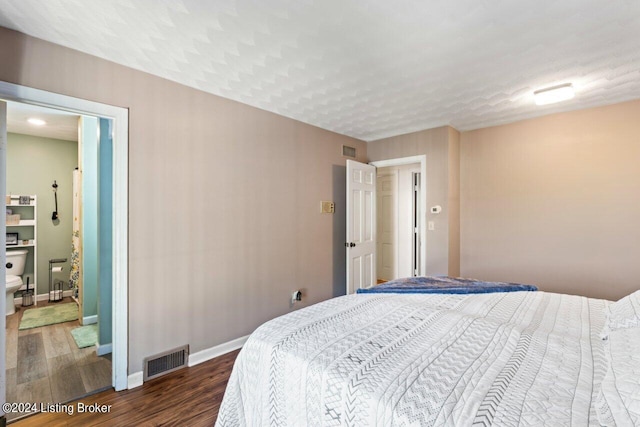 bedroom with a textured ceiling and dark hardwood / wood-style flooring