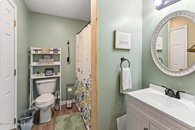 bathroom with toilet, hardwood / wood-style flooring, vanity, and curtained shower