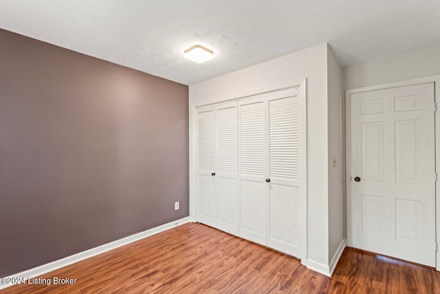 unfurnished bedroom featuring wood-type flooring, a closet, and a textured ceiling