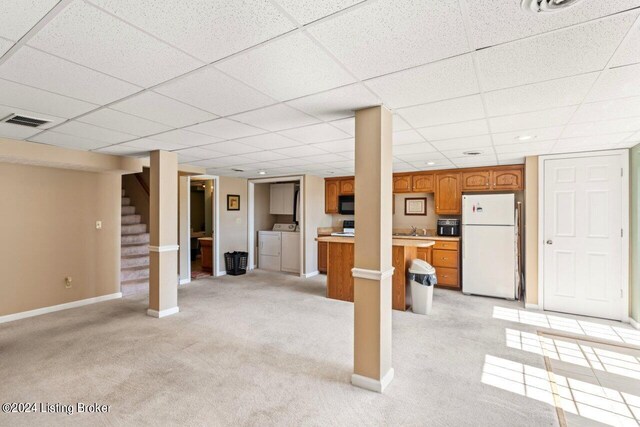 basement featuring light carpet, sink, separate washer and dryer, and white fridge