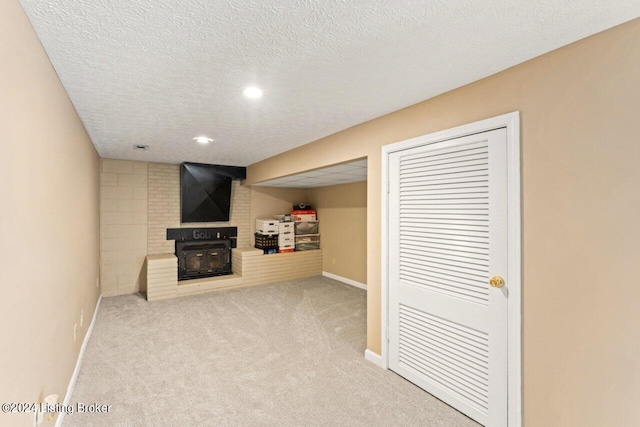 basement with light colored carpet, a large fireplace, and a textured ceiling