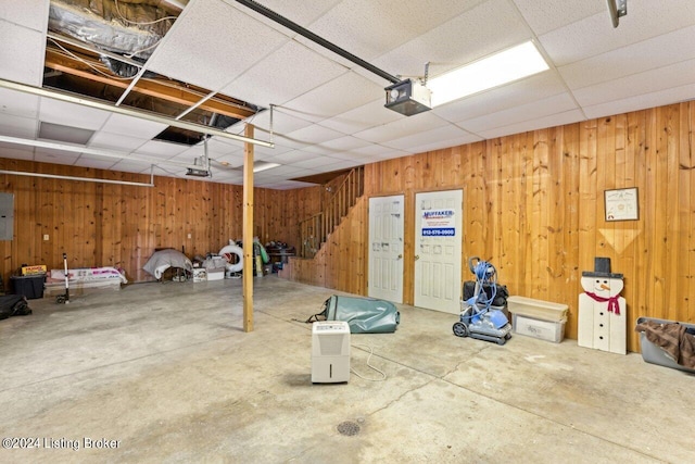 garage with electric panel, wooden walls, and a garage door opener