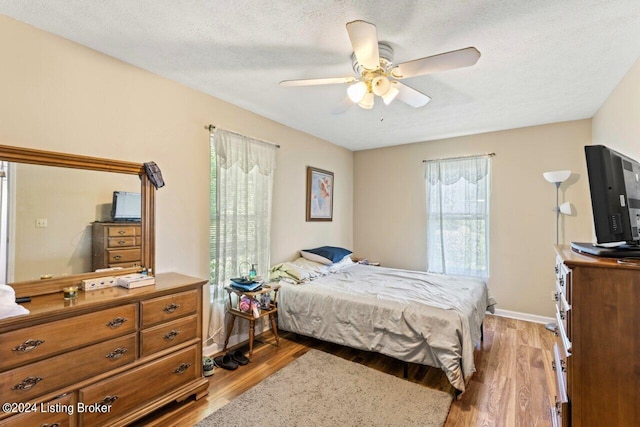 bedroom with light hardwood / wood-style floors, a textured ceiling, and ceiling fan