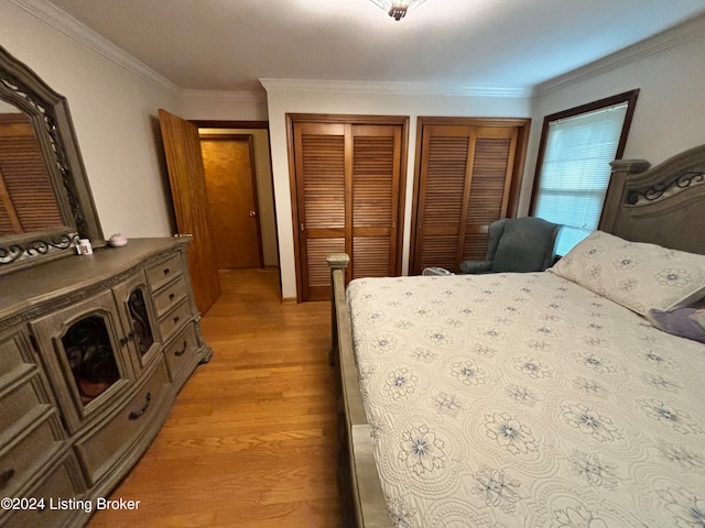 bedroom with multiple closets, crown molding, and light hardwood / wood-style flooring