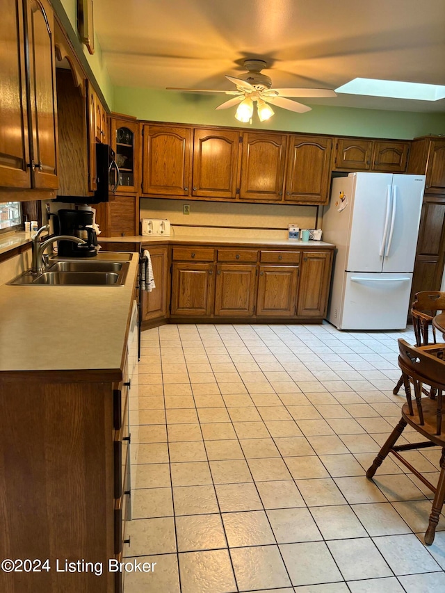 kitchen with a skylight, light tile patterned floors, white refrigerator, and ceiling fan