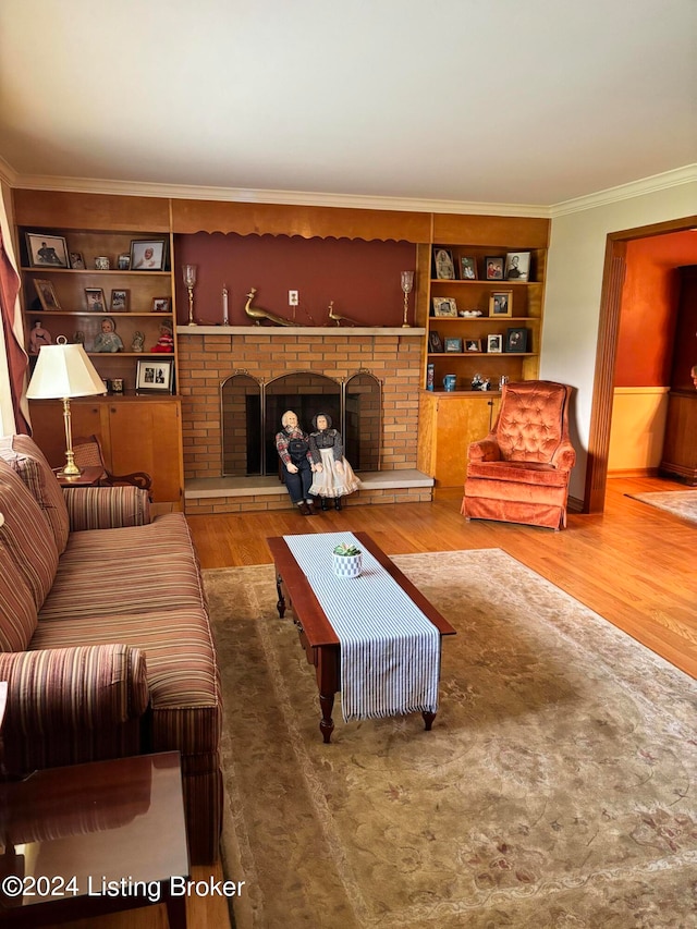 living room with built in features, ornamental molding, a brick fireplace, and hardwood / wood-style flooring