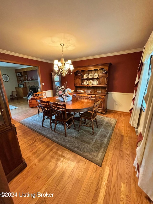 dining room with light hardwood / wood-style floors, crown molding, and an inviting chandelier