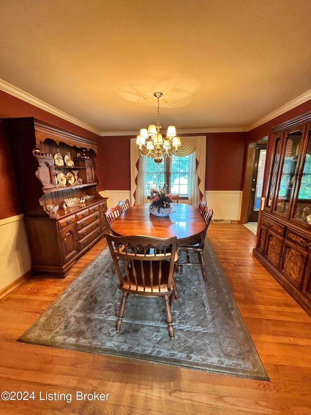 dining space featuring ornamental molding, a notable chandelier, and hardwood / wood-style floors