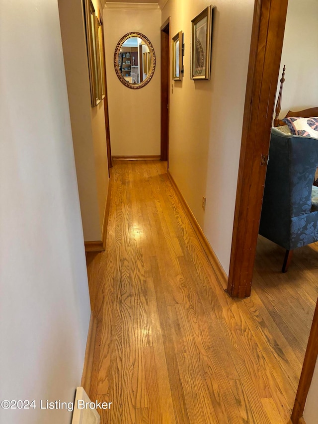 hall with light wood-type flooring and ornamental molding