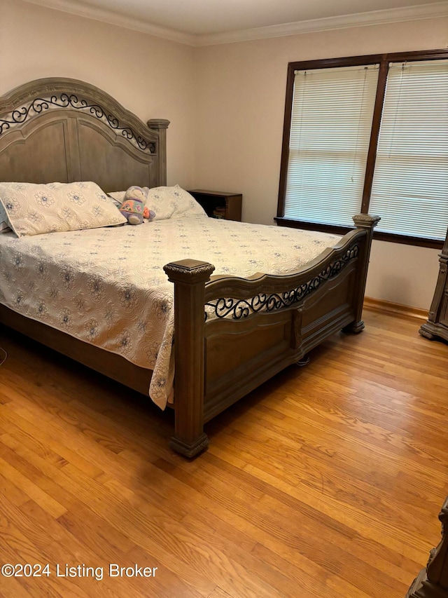 bedroom featuring ornamental molding and light wood-type flooring