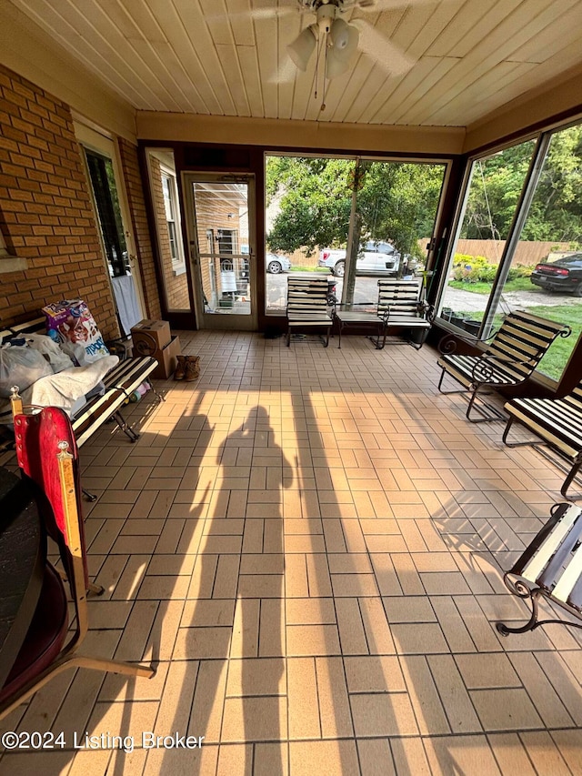 unfurnished sunroom featuring wood ceiling and ceiling fan