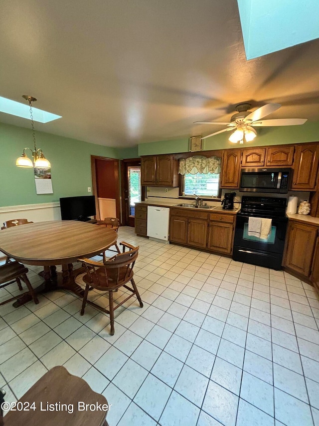 kitchen featuring white dishwasher, light tile patterned floors, ceiling fan with notable chandelier, a skylight, and electric range