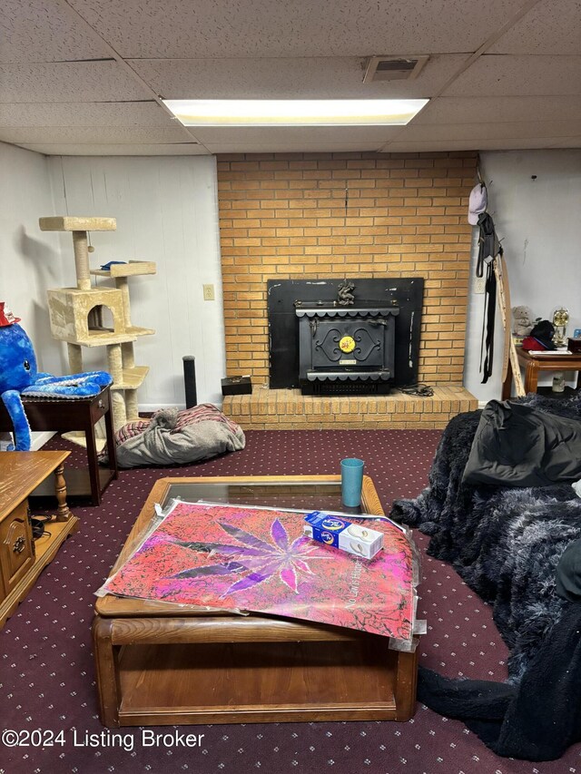 living room featuring a brick fireplace, brick wall, carpet floors, and a paneled ceiling