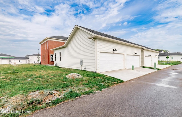 view of side of property featuring a garage and a lawn