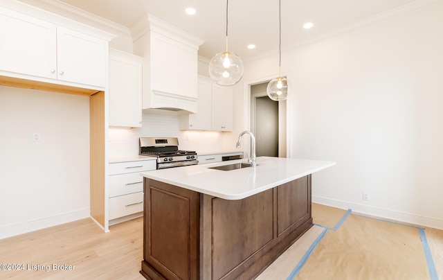 kitchen featuring sink, white cabinetry, hanging light fixtures, a center island with sink, and stainless steel range with gas cooktop