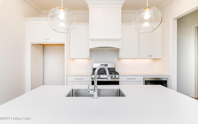 kitchen with pendant lighting, crown molding, stainless steel gas range oven, white cabinets, and decorative backsplash