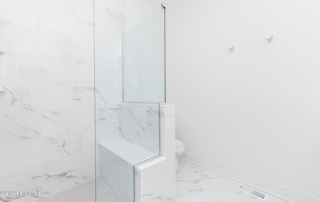 bathroom with a tile shower and toilet