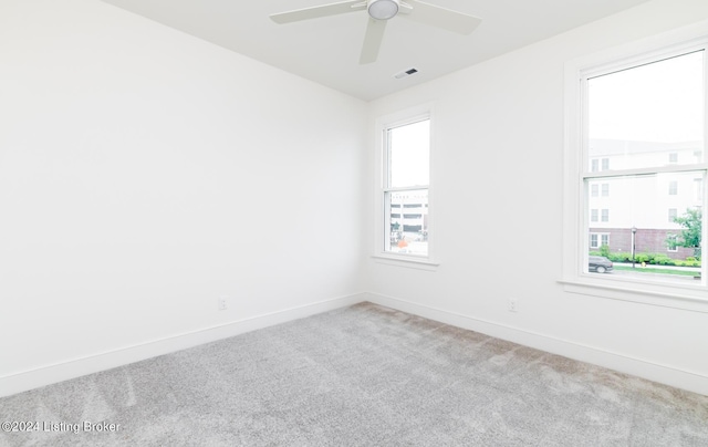 spare room featuring ceiling fan, light colored carpet, and a healthy amount of sunlight