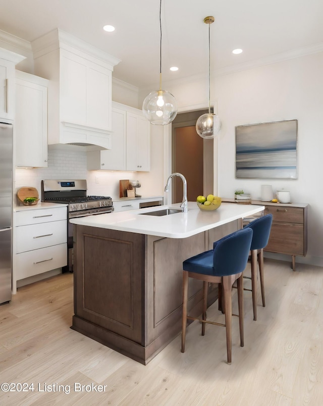 kitchen with stainless steel appliances, a kitchen island with sink, sink, and white cabinets