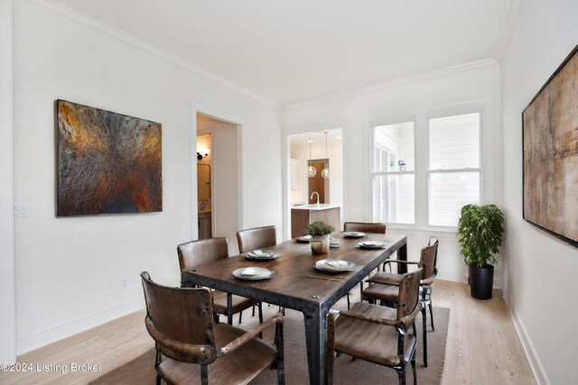 dining space with crown molding and light hardwood / wood-style flooring