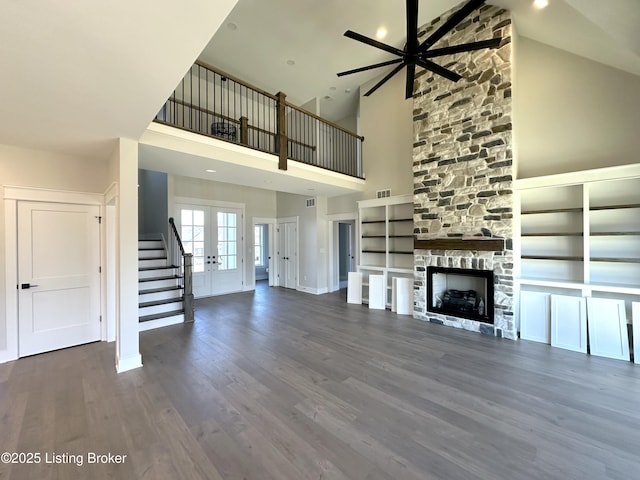 unfurnished living room with baseboards, visible vents, dark wood-type flooring, french doors, and a fireplace