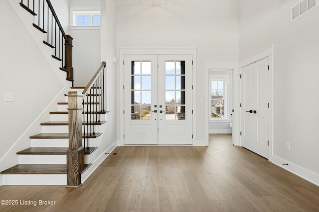 entrance foyer with visible vents, french doors, wood-type flooring, a high ceiling, and stairway