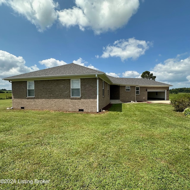 back of house featuring a lawn and a garage